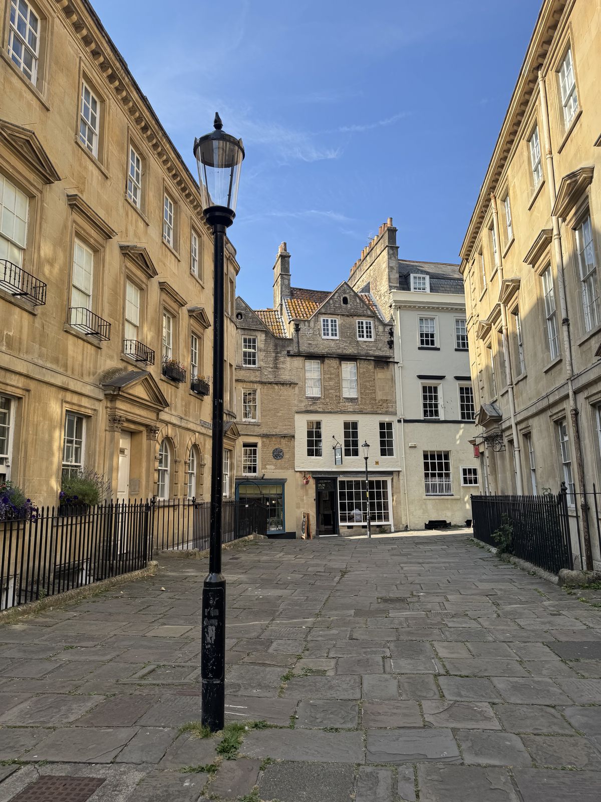 A quiet flagstone lane in Bath with a gas lamp and honey-coloured Georgian stone terraces