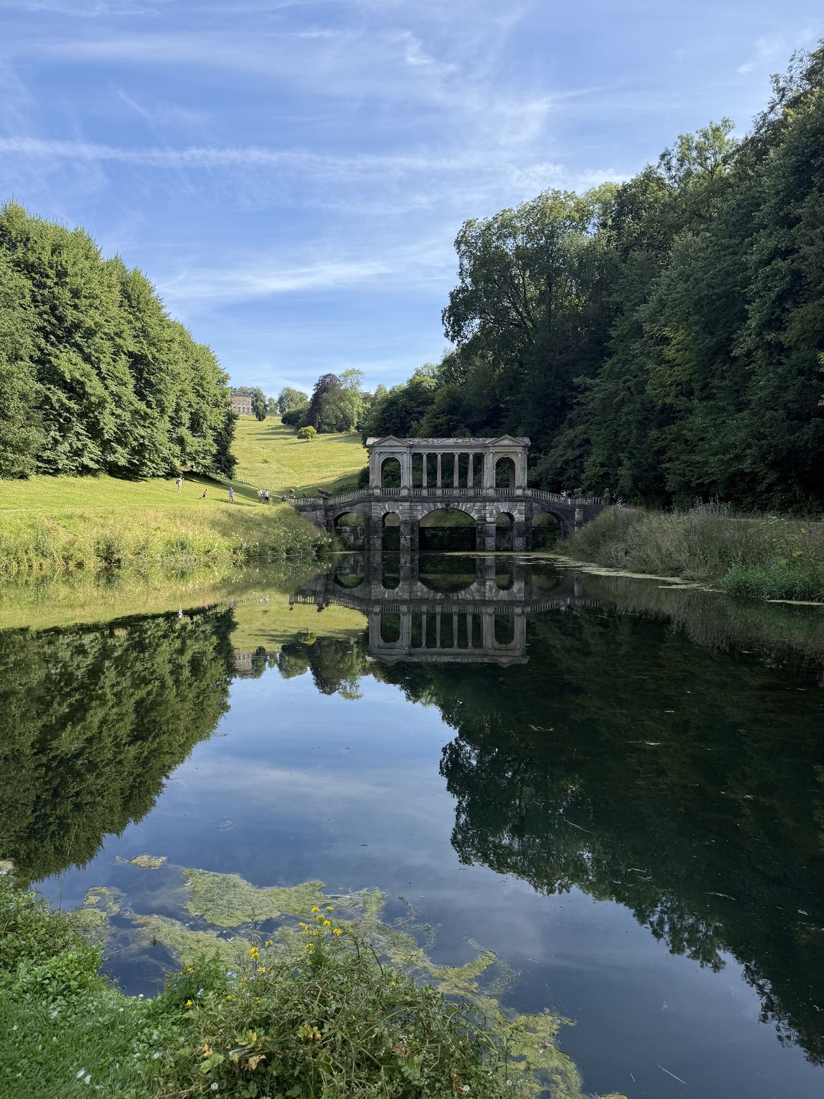 The Palladian Bridge at Prior Park reflected in the lake below the Bath hills