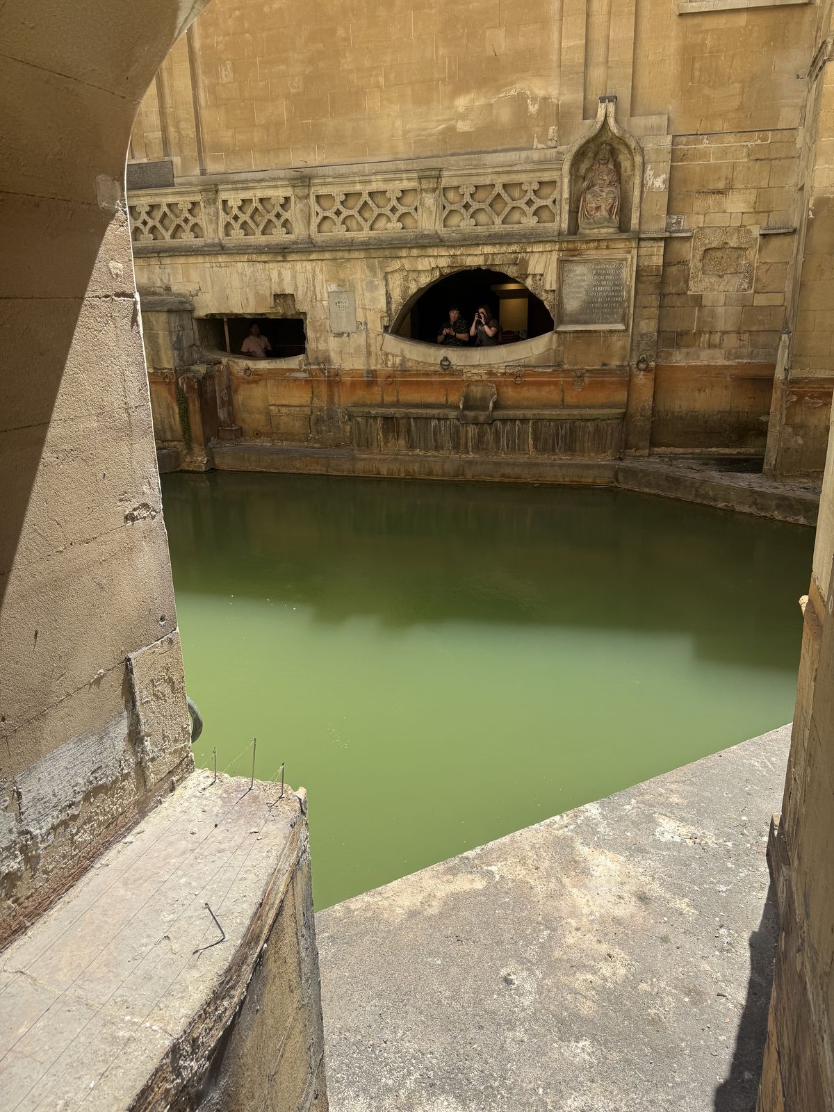 The King's Bath spring at the Roman Baths, steaming thermal water below old stonework