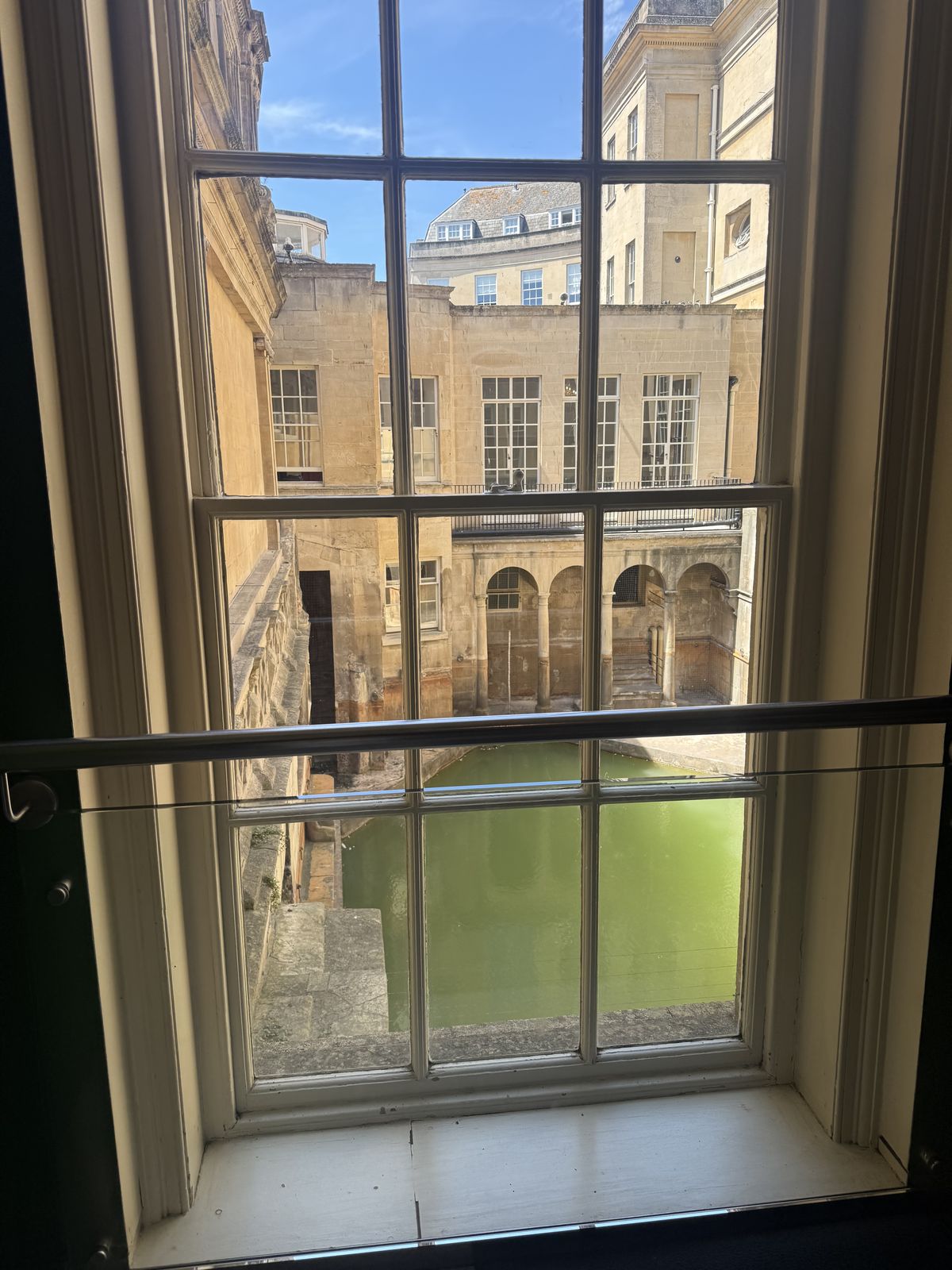 The Great Bath at the Roman Baths in Bath, seen through a Georgian sash window